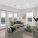 Virtually staged image of the living room with a couch, coffee table and TV mounted on the wall